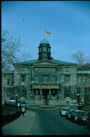 In 1811, James McGill bequeathed 10,000£ and his forty-six acre estate, which stretched from Dr. Penfield Avenue to Cathcart Street, to the Royal Institution for the Advancement of Learning, a body which then governed the Quebec education system. This was done with the understanding that the land and money would be put towards a University to be created within ten years of McGill's death or the whole would become the property of McGill's heirs. James McGill died in 1813, but at that time, the Royal Institution had neither trustees nor a board and so did not have the power to execute the stipulations of  the will. Ultimately, it took another sixteen years, several lawsuits, and many delays before classes were started.

In June of 1829, classes were started in Burnside Hall, the late McGill's house, which was named after a small brook that meandered through the property. In this year, McGill College, as it was then called, annexed the Montreal Medical Institution so that it could grant degrees and McGill could have students. In 1837, with the property deed and the bequest in hand, the Royal Institution and McGill's new Board of Governors decided to erect the first buildings on campus, yet each faction had a different idea of what was required. The Royal Institution held a competition among several architects who were asked to design an edifice that befitted a University, met its teaching and housing needs, yet was not too expensive. In 1839, John Ostell, a prominent Montreal architect of British origin, won the competition and, after much strife between the Institution and the Board, construction began.

In 1843, the central and east portions of the McGill College Building (now the Arts Building) were complete, but the Royal Institution was fast running out of money and so halted any further work. It had been decided in 1839 that a third floor and a cupola would be added to the central block to provide more room, but the planned west wing would not be constructed nor would the corridors that were intended to connect the wings to the centre. Both the exterior and the interior of the two completed sections were designed in the Classical style. A pediment, supported by Tuscan columns, capped the central block and the library on the second floor of this block was decorated in the Greek manner. The central block contained the steward's apartment, the kitchen, the Governor's' council room, the library, the college Hall, and classrooms. The east section held the chapel and the vice-principal's residence. A two-storey portico with Doric columns was planned but was not built at the time. Before 1843, the Royal Institution, despite the protests of the Board, decided to sell the land south of Sherbrooke Street to raise enough money to finish the project.

In September of 1843, McGill College, in debt at the time, officially opened its central and east wings. Because they had never been properly finished, the roof began to leak, the rooms were cold and dimly lit, there were numerous rats in the walls, and several windows were broken. In 1852, the city started blasting for the McTavish reservoir which sent large rocks through the roof of the nearby McGill College Building; the staff and students sought refuge elsewhere. When the new principal, Sir William Dawson, arrived in 1855, he found the campus in a state of disorder. He later recalled, "I first saw [the college] in October 1855. Materially, it was represented by two blocks of unfurnished and partly ruinous buildings, standing amidst a wilderness of excavators' and masons' rubbish, overgrown with weeds and bushes. The grounds were unfenced and pastured at will by herds of cattle... The only access from town was by a circuitous and ungraded cart-track, almost impassable at night. The buildings had been abandoned..." (Frost, Stanley. McGill University for the Advancement of Learning 1 McGill-Queen's University Press 1980. 198)

Sir William Dawson, who lived in the east wing, immediately made it his responsibility to get the campus into shape. In 1860, he hired J.W. Hopkins to add a one-storey wooden portico with Doric columns to the central block. Since Dawson was well connected with the elite of Montreal, he persuaded Sir William Molson to donate the west wing of  the McGill College Building, named Molson Hall, and the connecting corridors built in the same Classical style as the original units. These held the convocation hall, library, classrooms, chemistry labs, and a small museum and left more room for residents. Of particular interest was the library on the second floor of Molson Hall which featured oak shelves and Classical columns.

In 1925, Fetherstonhaugh and McDougall were hired to extensively renovate what, by then, was called the Arts Building. Until this time, the building had suffered problems with ventilation, heating, and overcrowding. Fetherstonhaugh transformed the first floor of the central block into a large entrance lobby with black marble columns and a floor of pink Tennessee marble. A coloured globe lamp hangs inside the entrance foyer surrounded by the signs of the zodiac, declaring the worldliness of the Faculty of Arts. Moyse Hall, a large lecture and play theatre adorned by ten electric bronze chandeliers and bas reliefs by Henri Herbet, was added behind the central wing of Arts. The rest of the building was divided into suites, one for each Arts Department. Outside, the wooden portico was dismantled and rebuilt in yellow stone with Doric columns and Molson Hall's roof was raised by one floor. Although the interior was greatly changed, the exterior remained the same. The east wing of the Arts Building was named Dawson Hall after Sir William Dawson, its most permanent occupant. It serves as an Administration facility today.