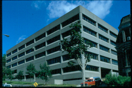 The Ernest Rutherford Physics Building, named after one of McGill's most famous radiation physicists, was constructed in 1977 to provide this department with more modern labs and equipment than could be housed in the Macdonald Physics Building. This five-storey structure, built by Dobush, Stewart, Hein, Longpré, Marchand, and Goudreau, stands on University, across the way from the Eaton Electronics Laboratory (recently demolished) and the Foster Radiation and Cyclotron Building. Dobush and Stewart were two of the architects commissioned for McLennan Library and Stewart Biology and so were already familiar with the style of the campus. The Rutherford Building consists of prefabricated concrete slabs attached to a steel frame. Special precautions were taken to make the building as tremor free and stable as possible due to the nature of the experiments carried out here. The concrete is of a texture and colour that blends with the rest of the McGill campus structures. The only element of decoration in this functional building is the regular fenestration of tinted grey panels. The ground floor contains offices and large lecture rooms while the the upper storeys are given to offices and labs, some quite specialized. On the roof there are two astronomic observation domes used to study the stars on clear nights. Recently, the Ernest Rutherford Museum, which contains his desk and some of his equipment, was removed from the Macdonald-Stewart Library and was installed in the Ernest Rutherford Physics Building where it is still appreciated by modern physicists.